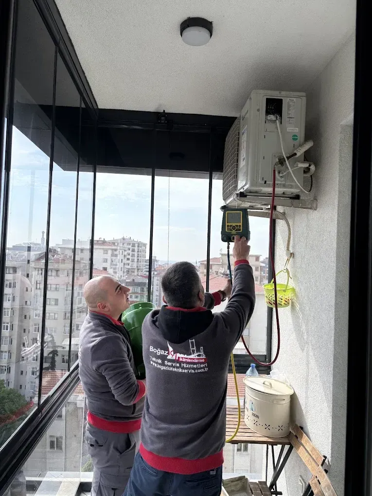 İki teknisyen dış cephede klima montajı sırasında ölçüm yapıyor