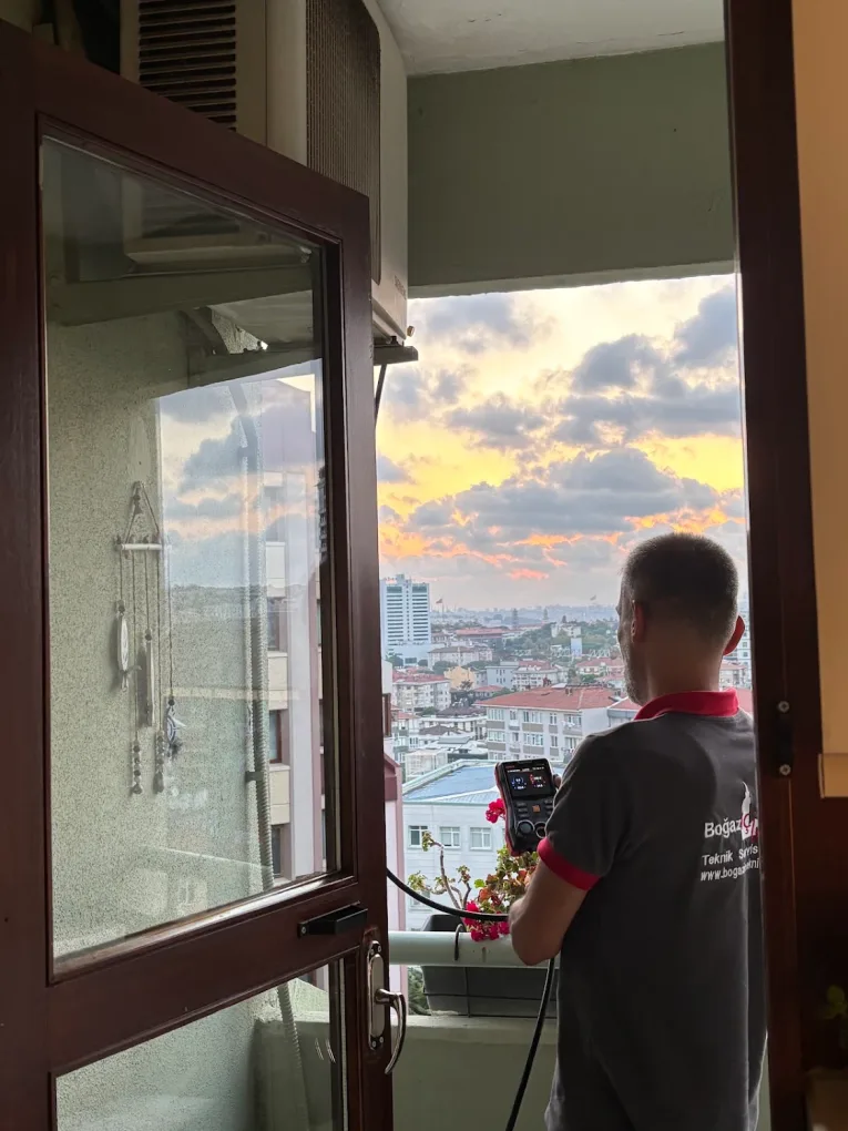 Teknisyen balkon penceresinde dijital ölçüm cihazıyla değer okuyor